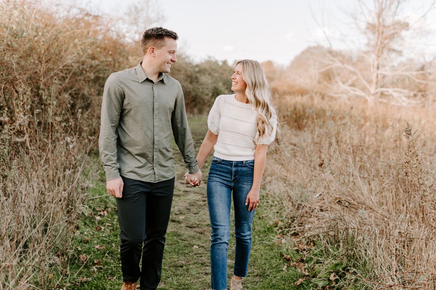 Casual couple strolling through autumn fields during golden hour.