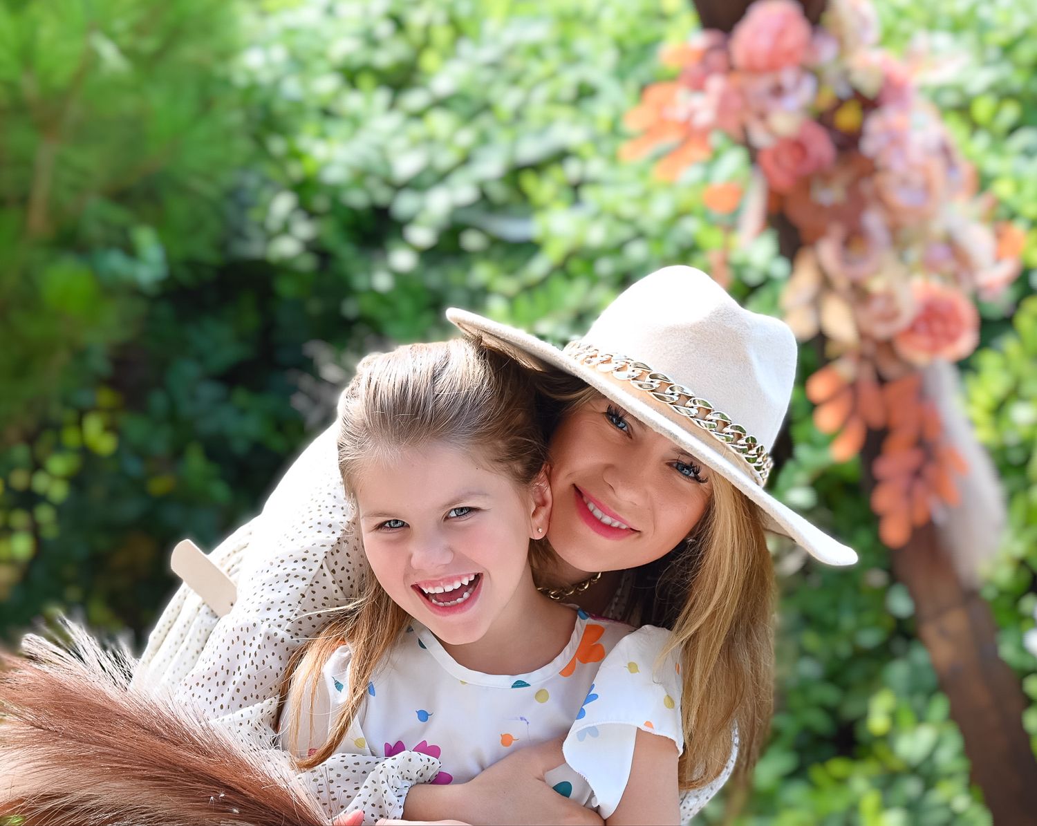 Two people share a joyful moment together in a garden with coral flowers blooming in the background.