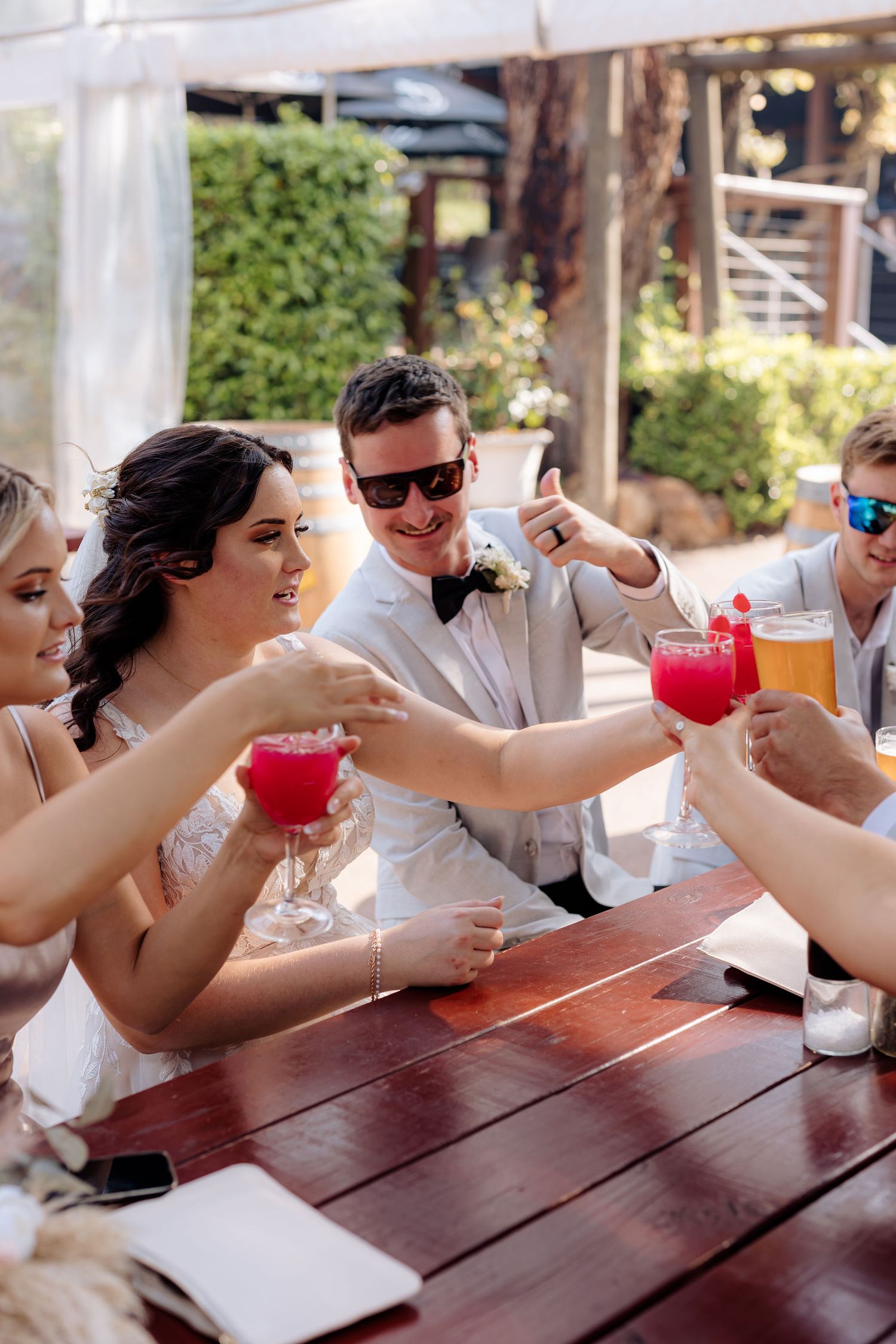 Wedding party toasting with colorful cocktails on an outdoor patio.