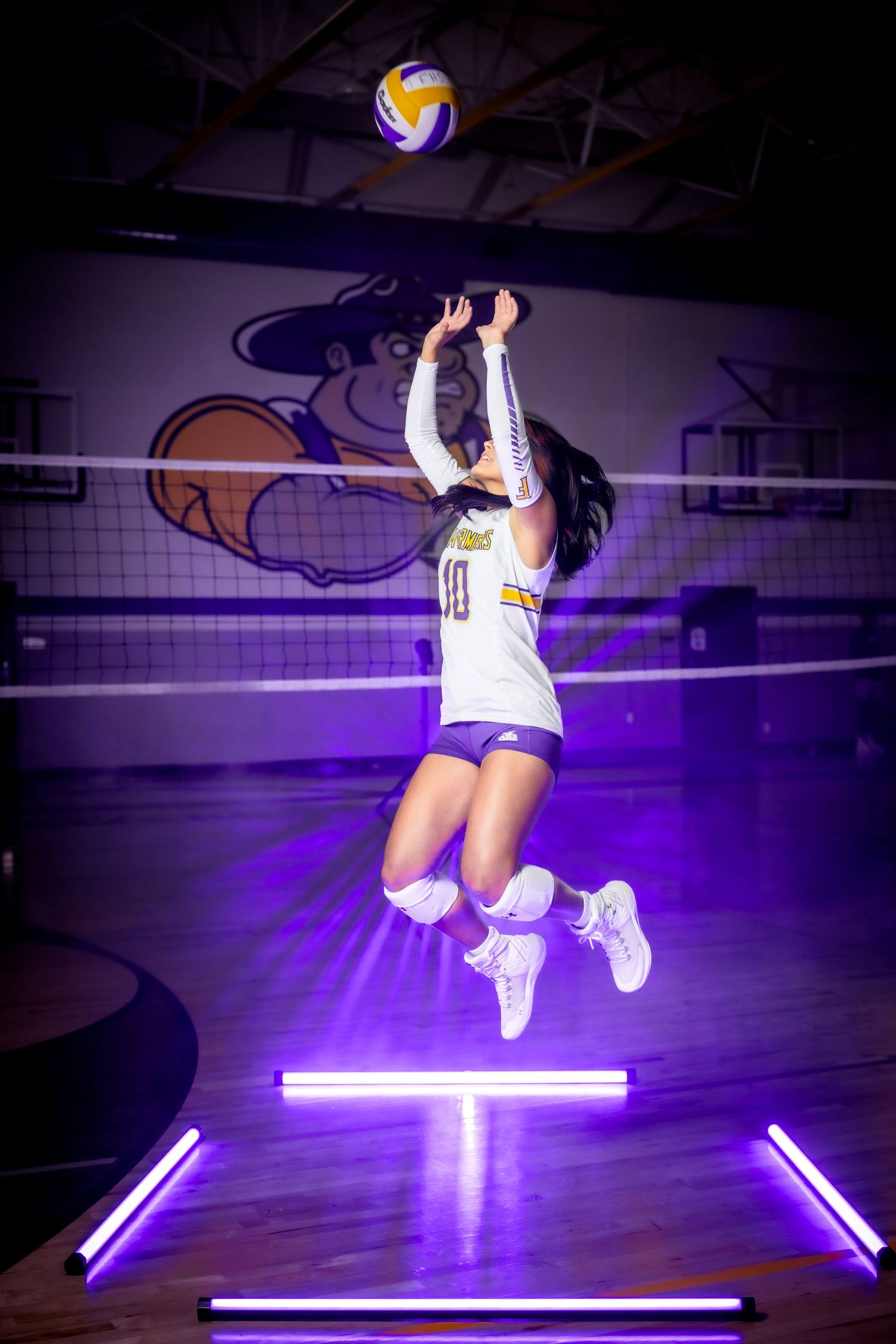 Dynamic volleyball action shot shows player jumping to set ball with purple lighting effects.