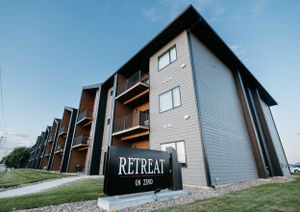 Modern gray apartment complex exterior with 'Retreat' signage.