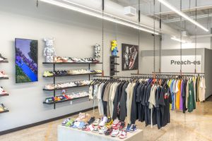 Modern retail store interior displaying sneakers on wall shelves and colorful clothing on racks.