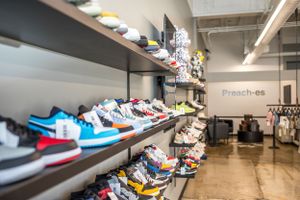 Retail display of colorful sneakers arranged on wall shelves in shoe store.