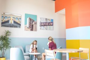 Colorful modern cafe interior with geometric wall design and seating areas.
