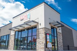 Contemporary retail storefront with stone accents and glass windows under blue sky.