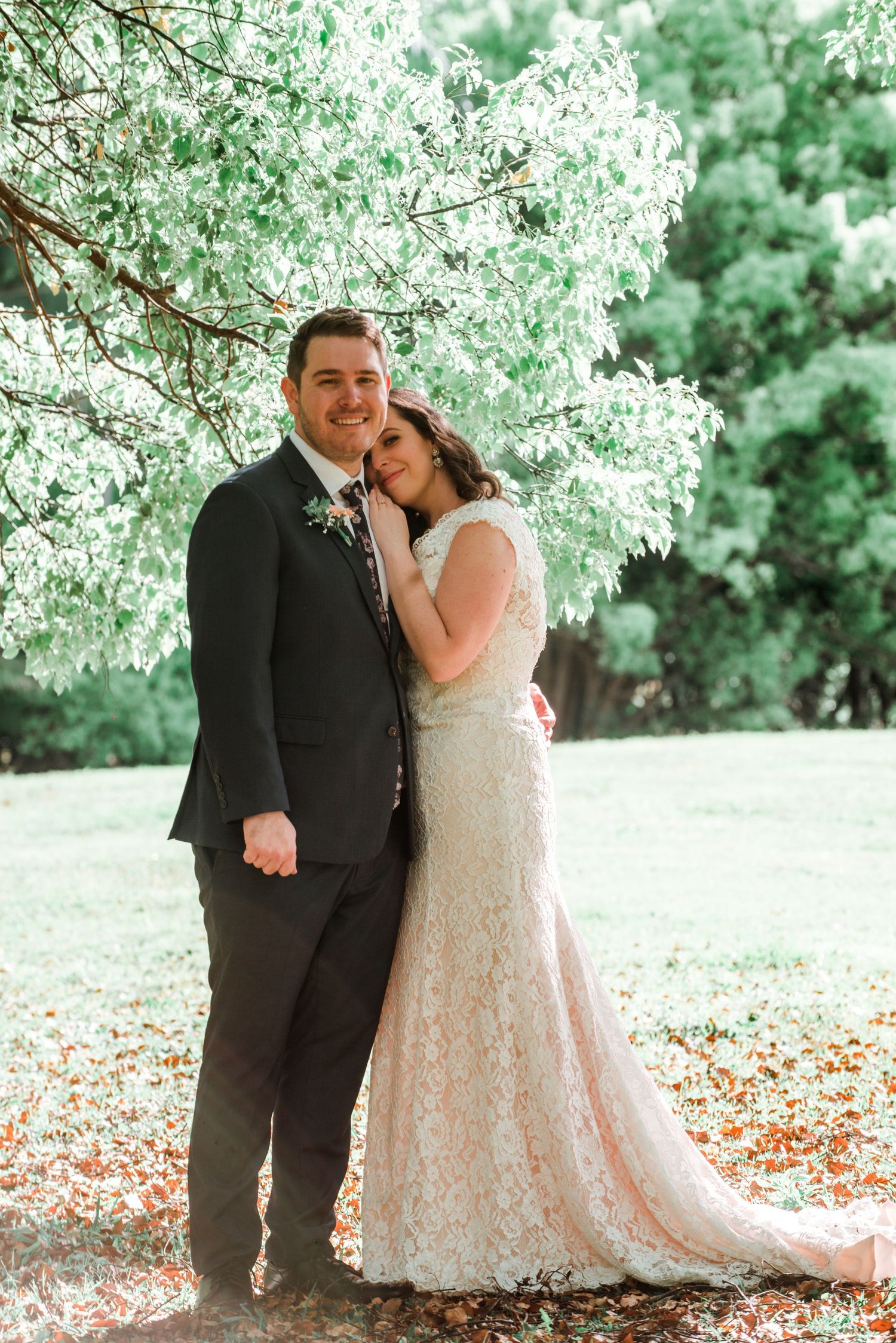 Newlyweds embrace under blooming white cherry blossom trees.