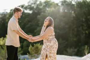 a couple in the mountains of arkansas holding hands facing each other and laughing