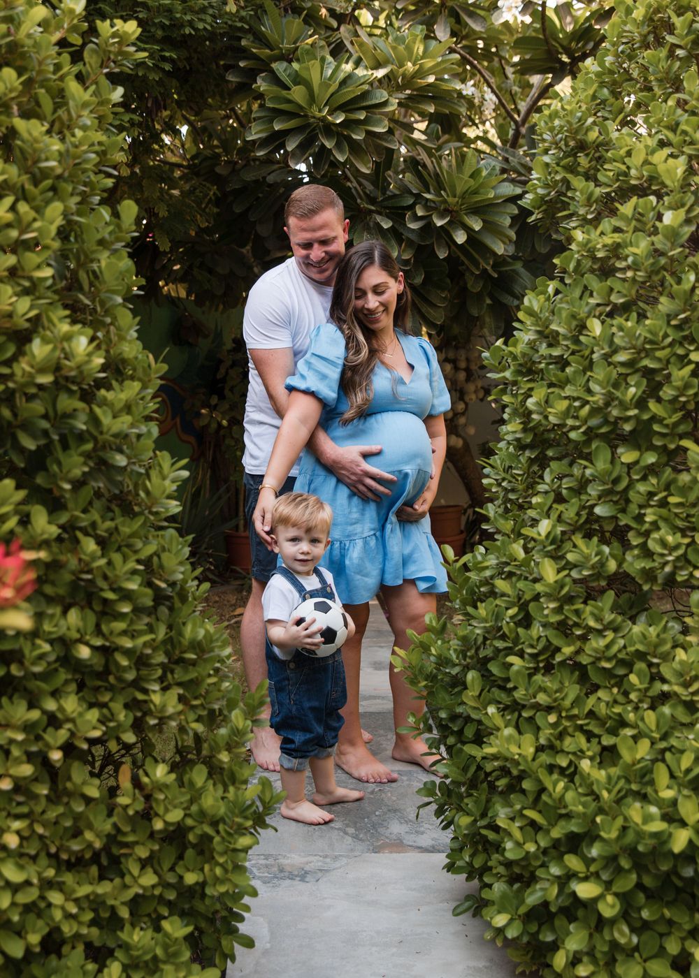 garden photoshoot with pregnant mother and toddler in blues and whites