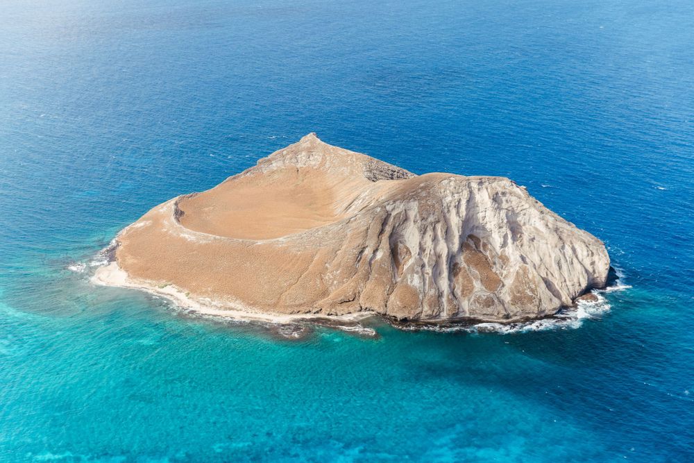 Aerial view of a dome-shaped island formation surrounded by turquoise waters.