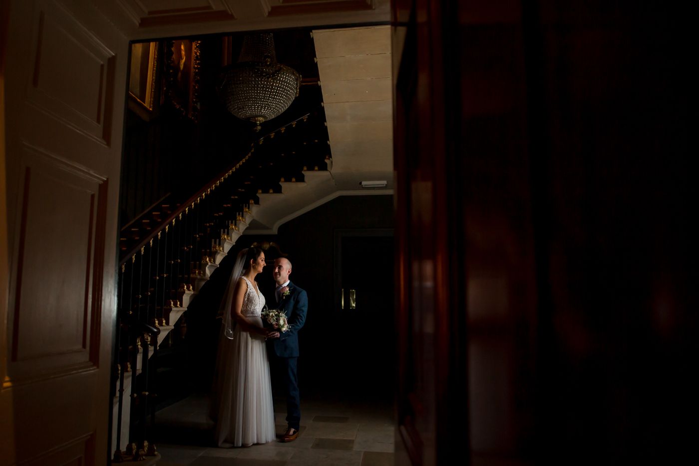 Dramatic silhouette photograph in a dark historic interior with architectural details.