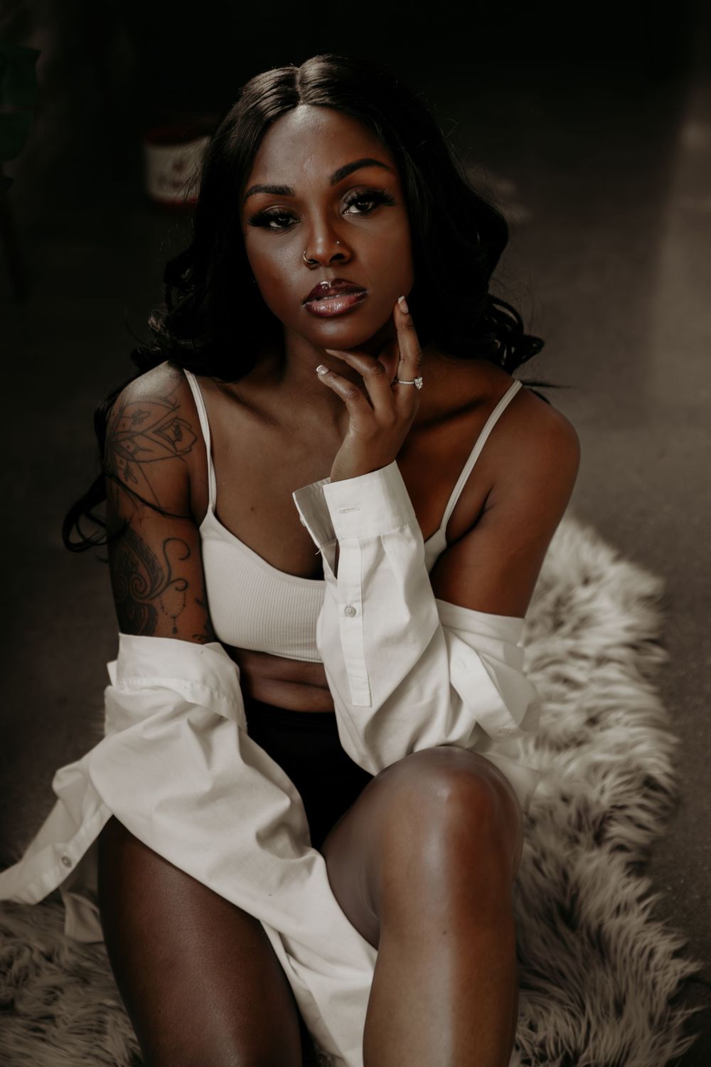 Moody portrait session with dramatic lighting and white clothing against exposed brick walls.