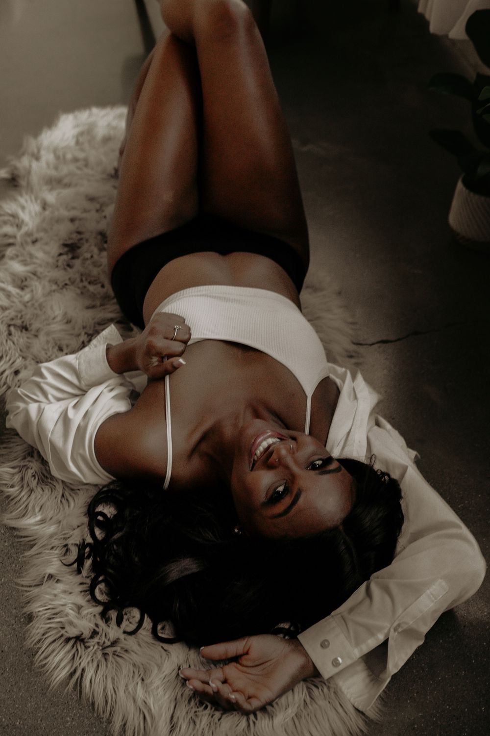Artistic black and white boudoir photos on a textured rug with moody lighting.