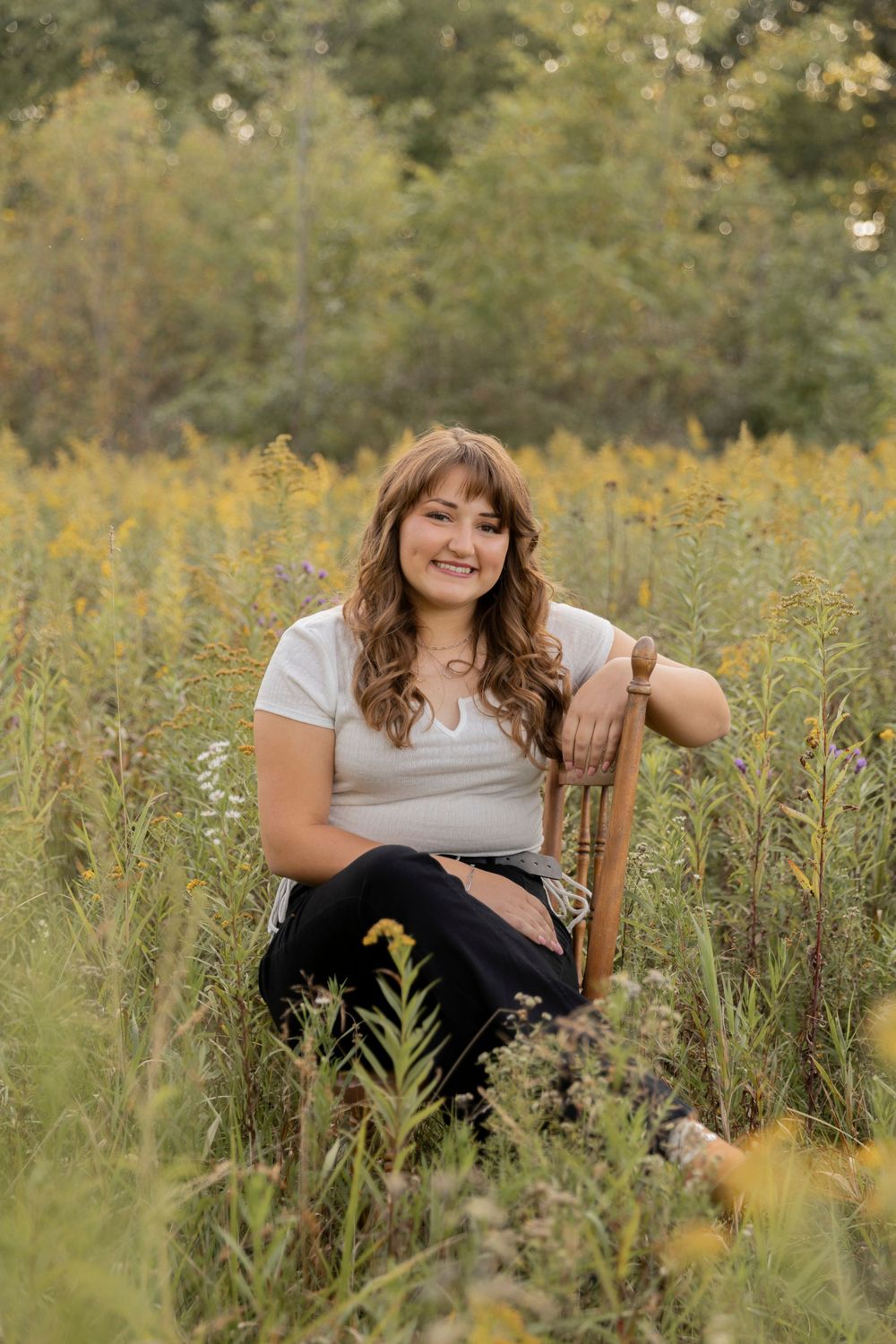 teenage girl sitting on a chair in a field of flowers