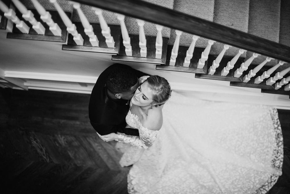 Aerial black and white photo of bride and groom embracing on a wooden staircase on their wedding day.