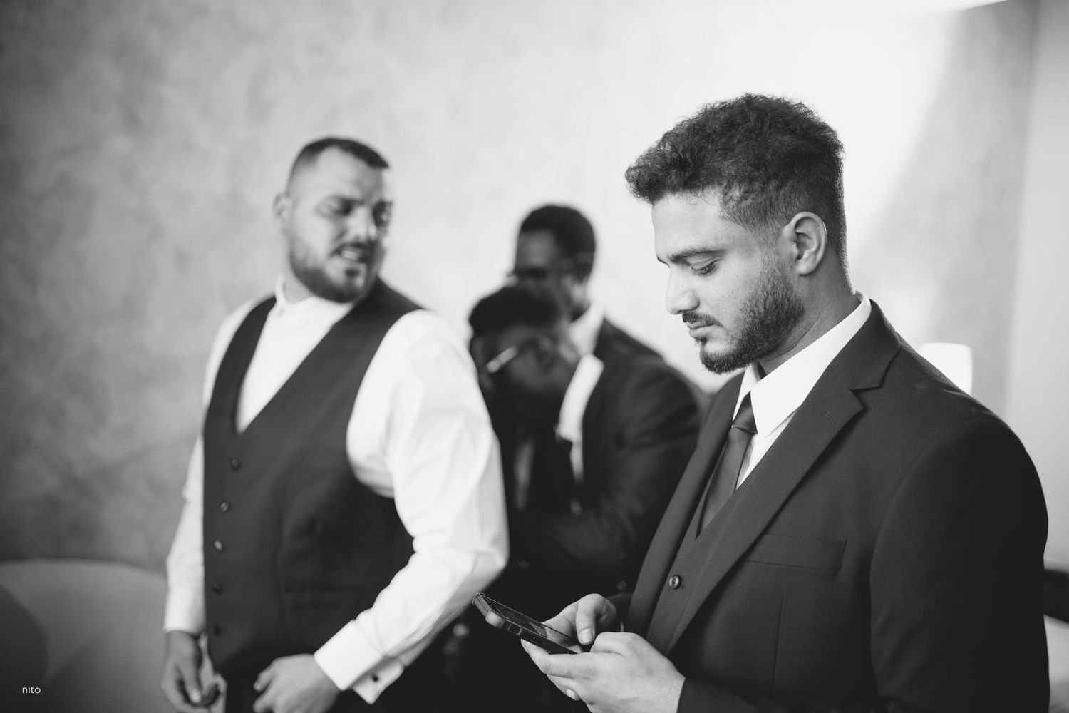 Black and white photo of groomsmen preparing before wedding ceremony.