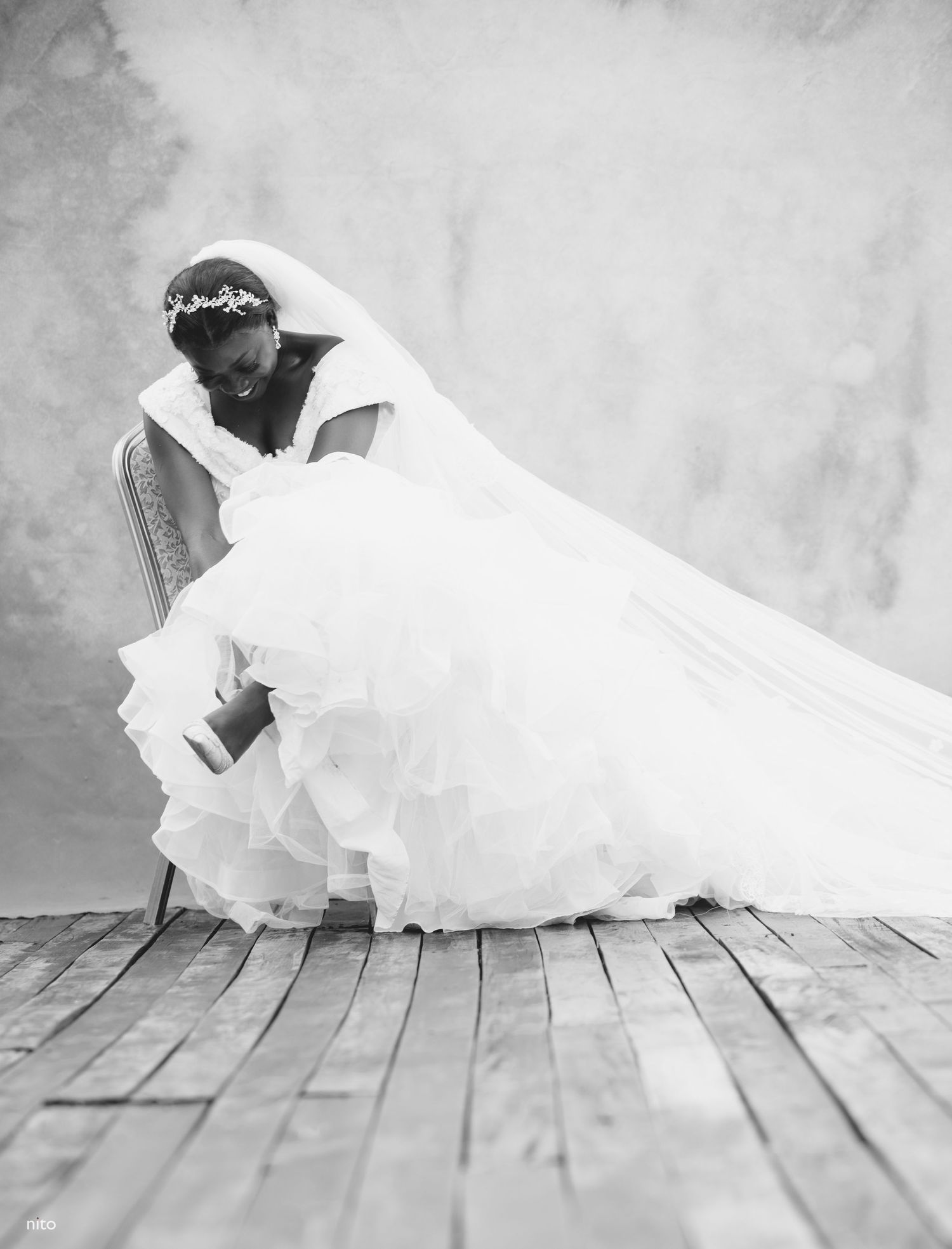 An elegant wedding dress with a flowing veil photographed in a dramatic black and white style.