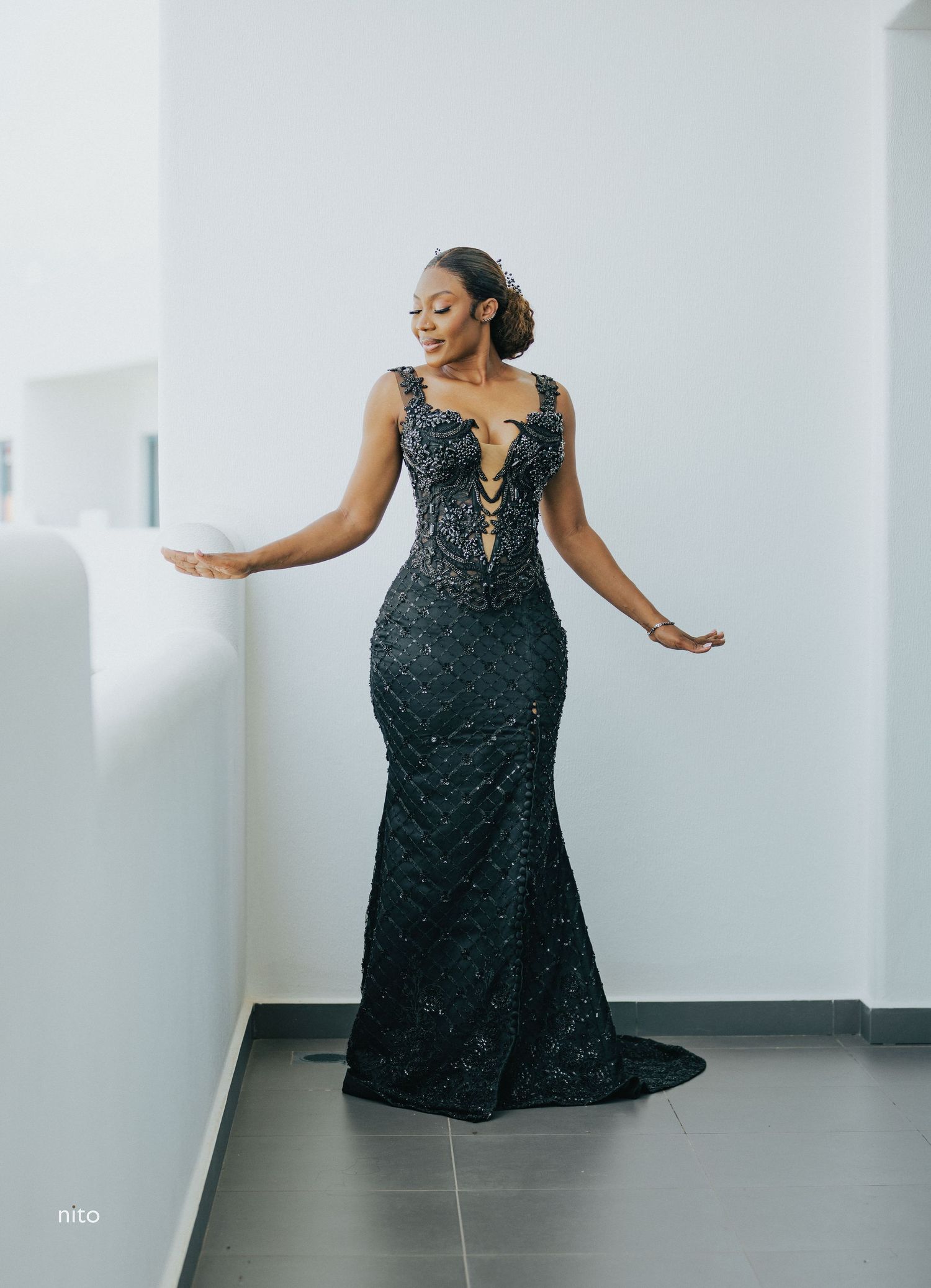 Full length view of stunning black beaded evening gown with train against white backdrop.