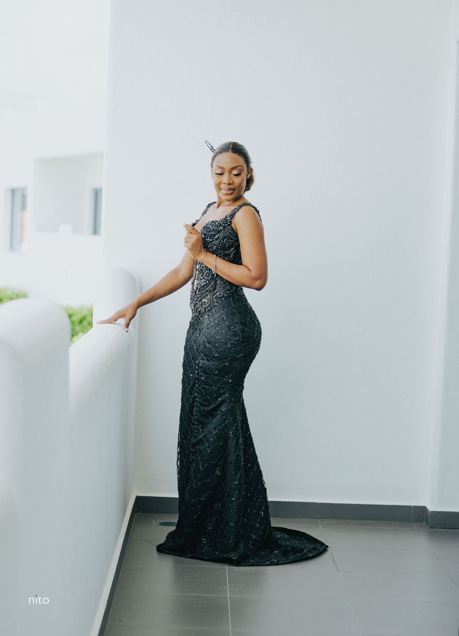Elegant pose in a form-fitting black sequined gown with sweep train.