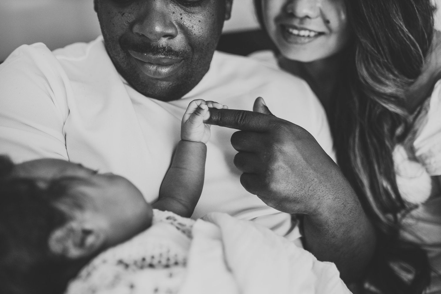 Black and white intimate photo of a couple holding hands and smiling together.