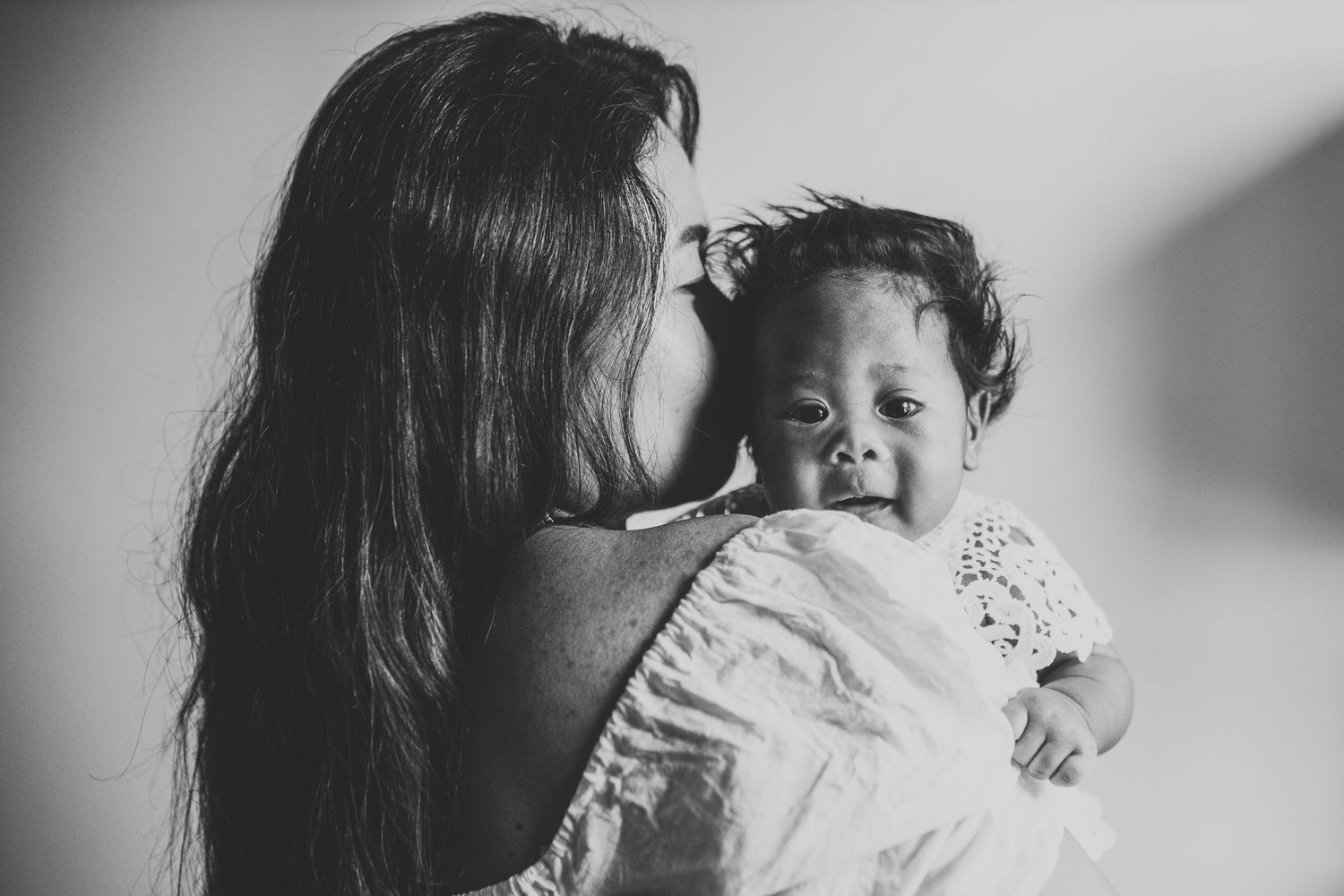 Black and white intimate portrait of parent and baby in tender moment.
