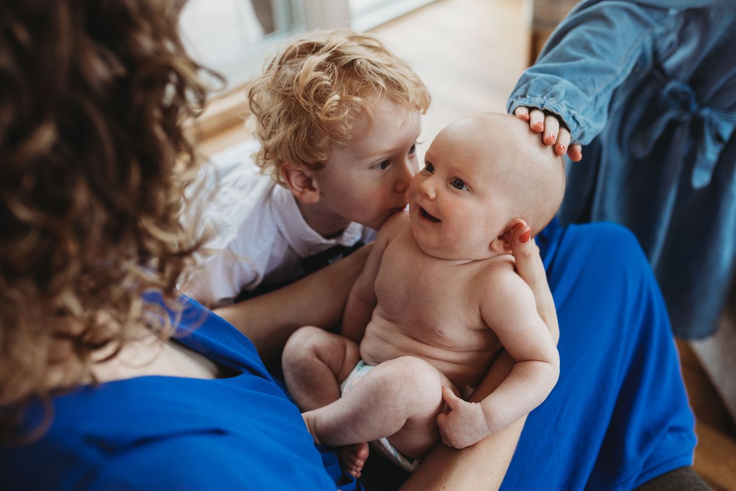 Two young children sharing an intimate moment on blue bedding.