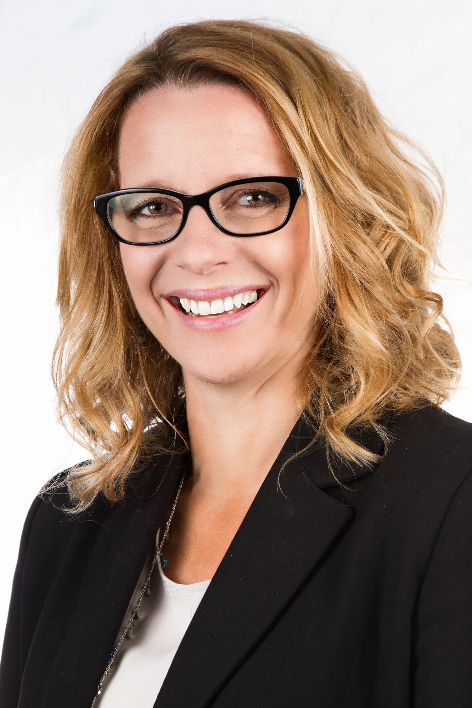 Professional headshot of a person in business attire with glasses and wavy blonde hair.
