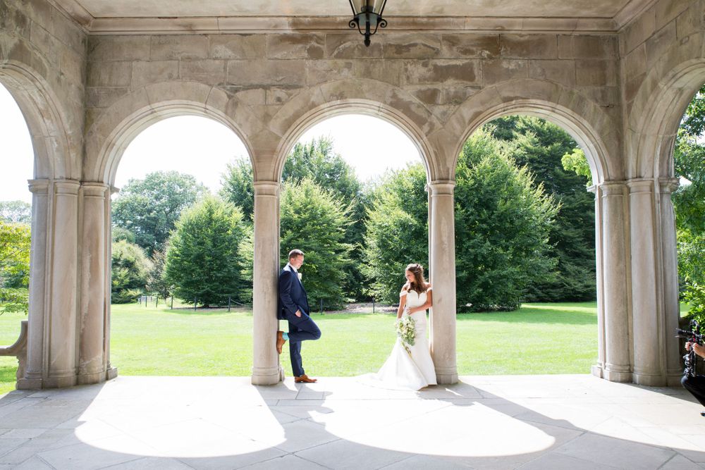 A romantic wedding photo under elegant stone arches with natural light streaming in.