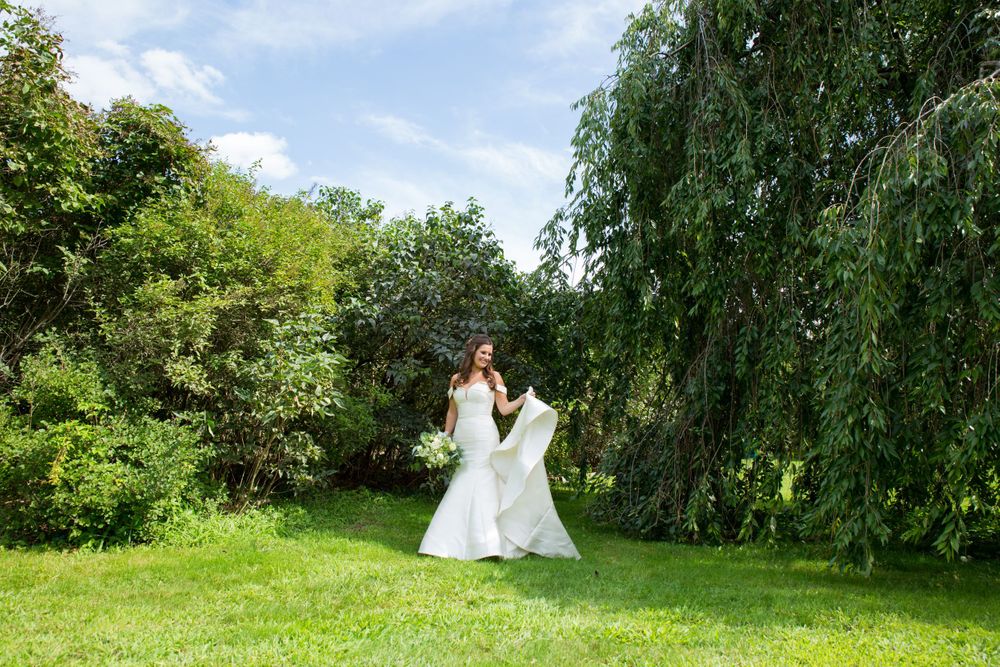 A bride twirls in her white dress in a lush green garden setting.