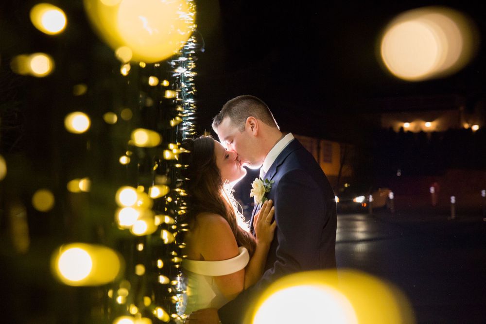 A romantic backlit nighttime portrait with bokeh lights creating a dreamy atmosphere.