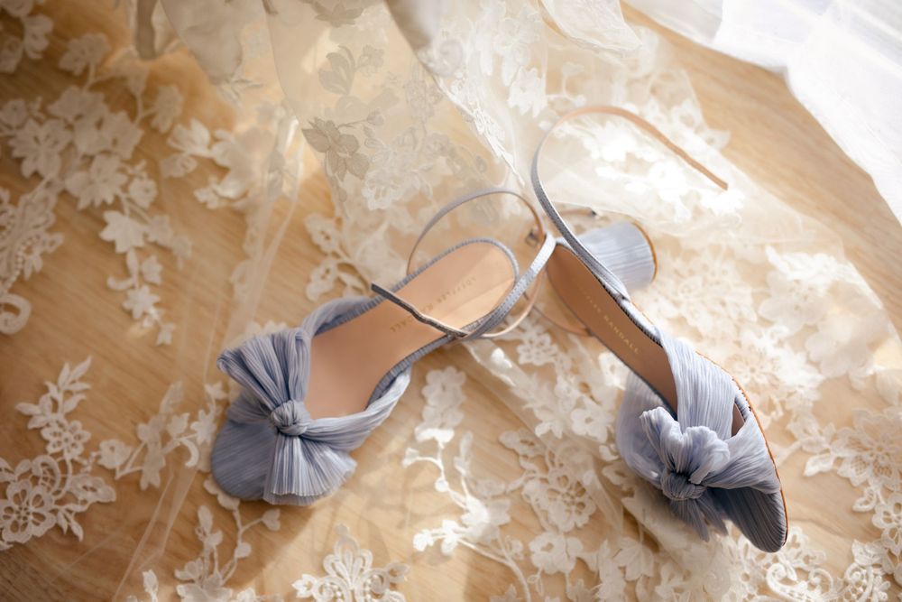 Elegant gray bow wedding shoes displayed on delicate lace fabric.