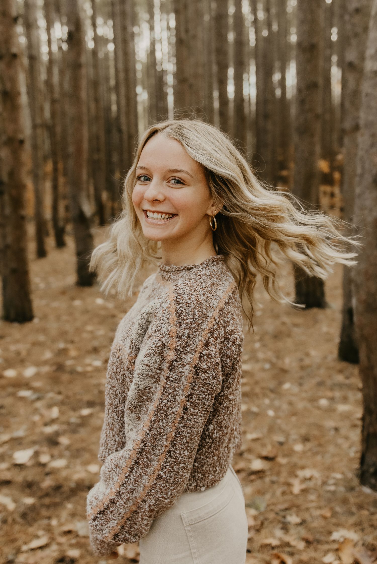 Portrait of a person in a cozy sweater with windswept hair in an autumn forest.