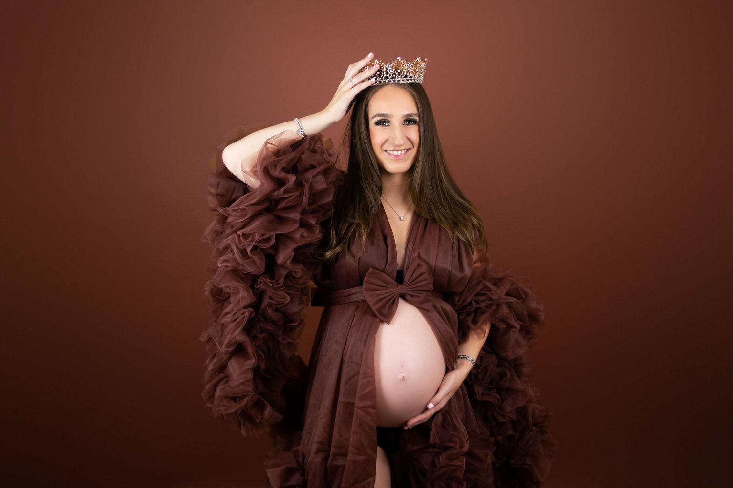 pregnant lady expecting a baby wearing a burgundy gown with a bow and a crown by photographer in Doncaster