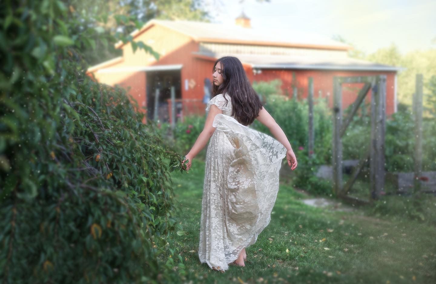 Portrait of young girl posing playfully in dress with barn in the background.