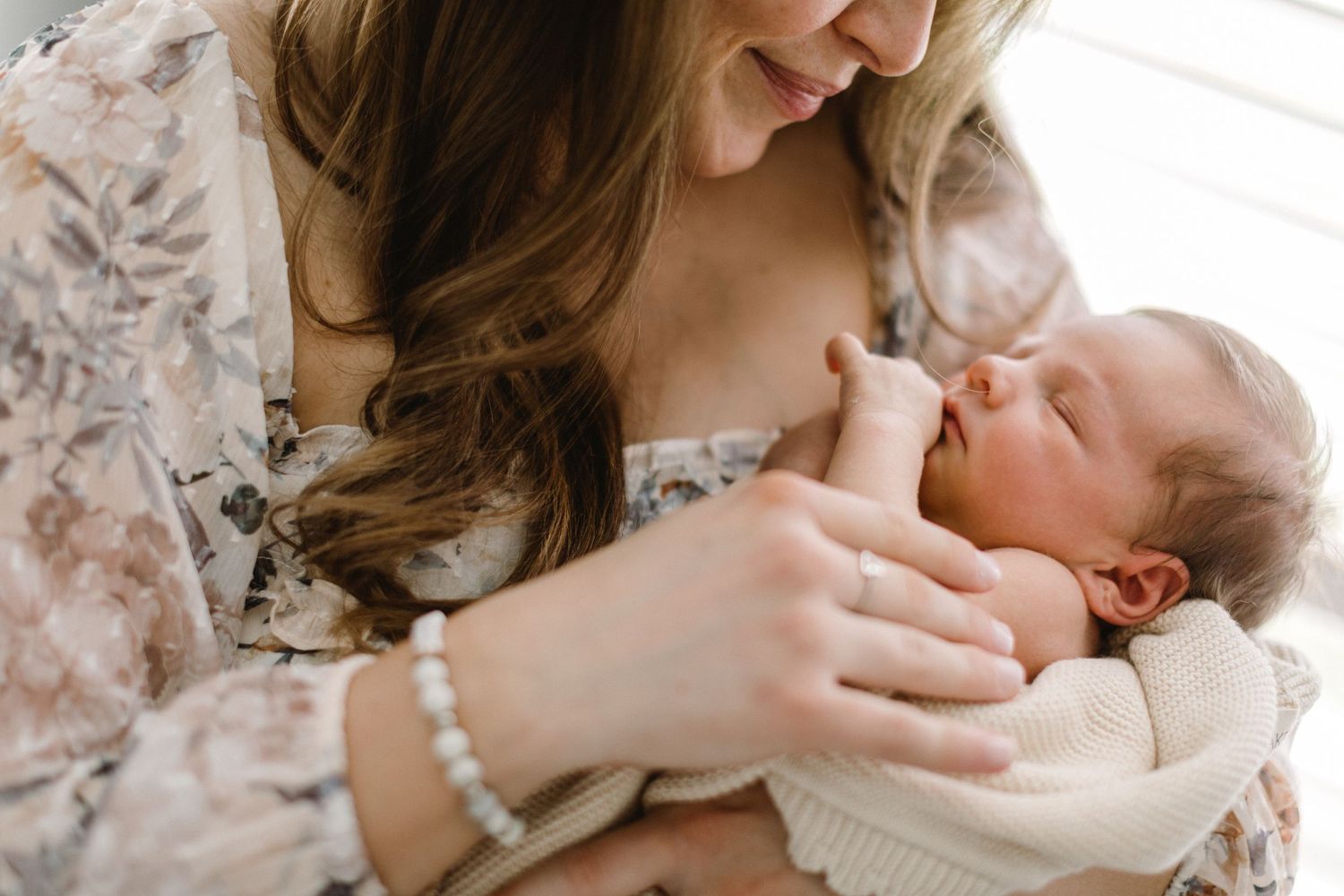 A tender moment between mother and newborn baby in soft natural light.