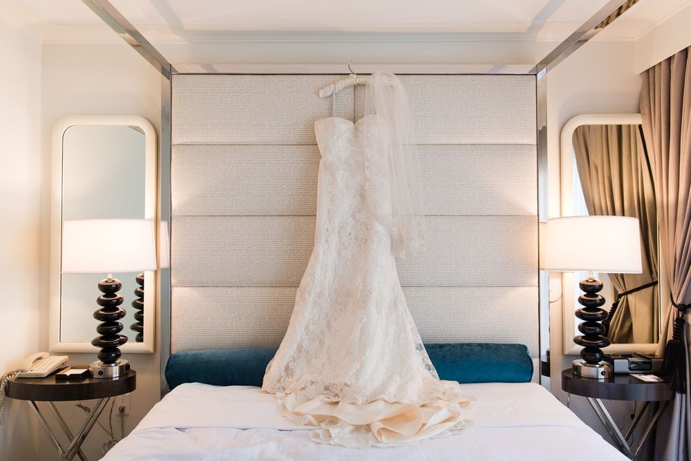Elegant white wedding dress displayed in luxurious hotel room interior.
