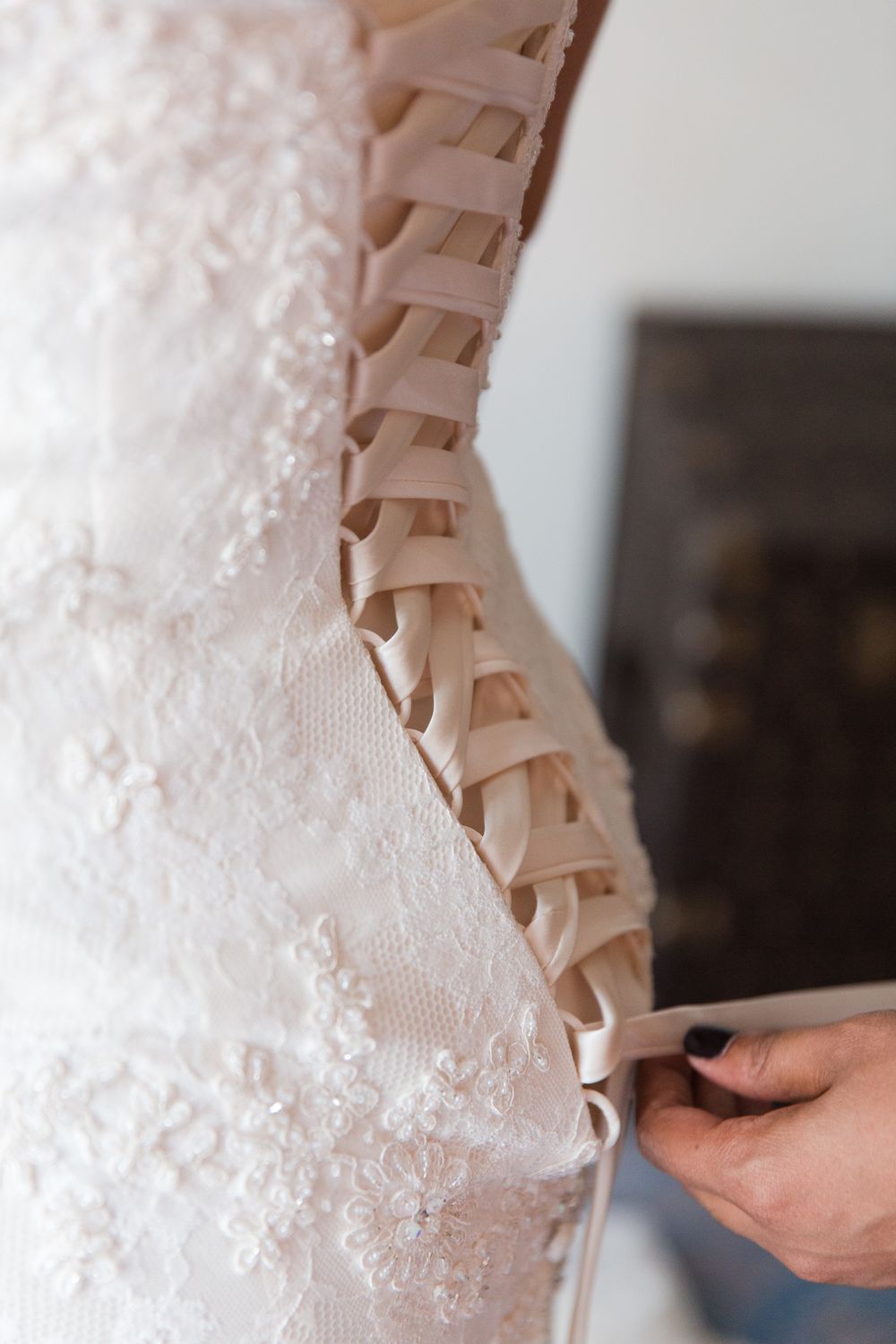 Close-up detail of corset back lacing on white lace wedding dress.