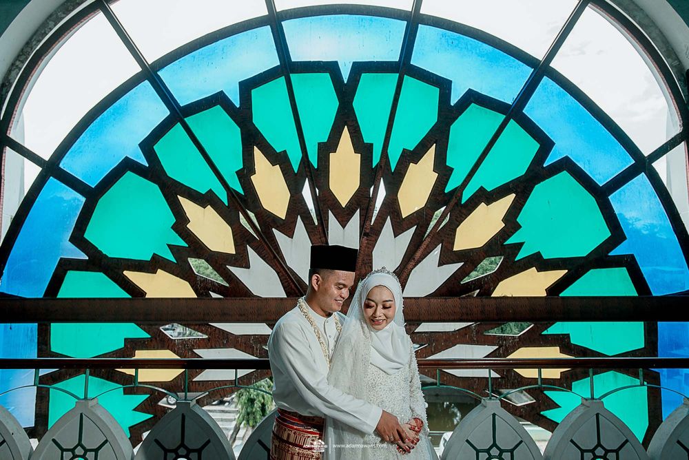 Traditional wedding portrait under ornate turquoise stained glass arch with geometric pattern.