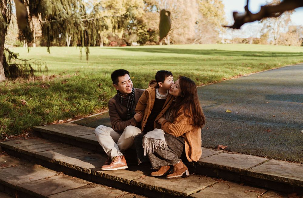 Group sitting together on wooden bench in park during golden hour.