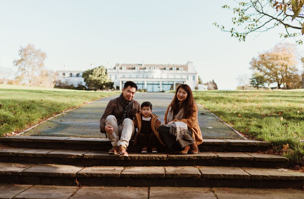 Family sitting together on outdoor stone steps with a building in the background.