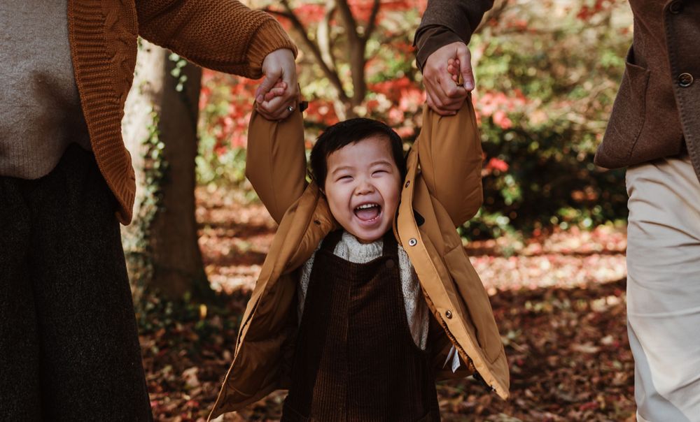 A joyful expression captured during outdoor playtime on a fall day with autumn leaves in the background.