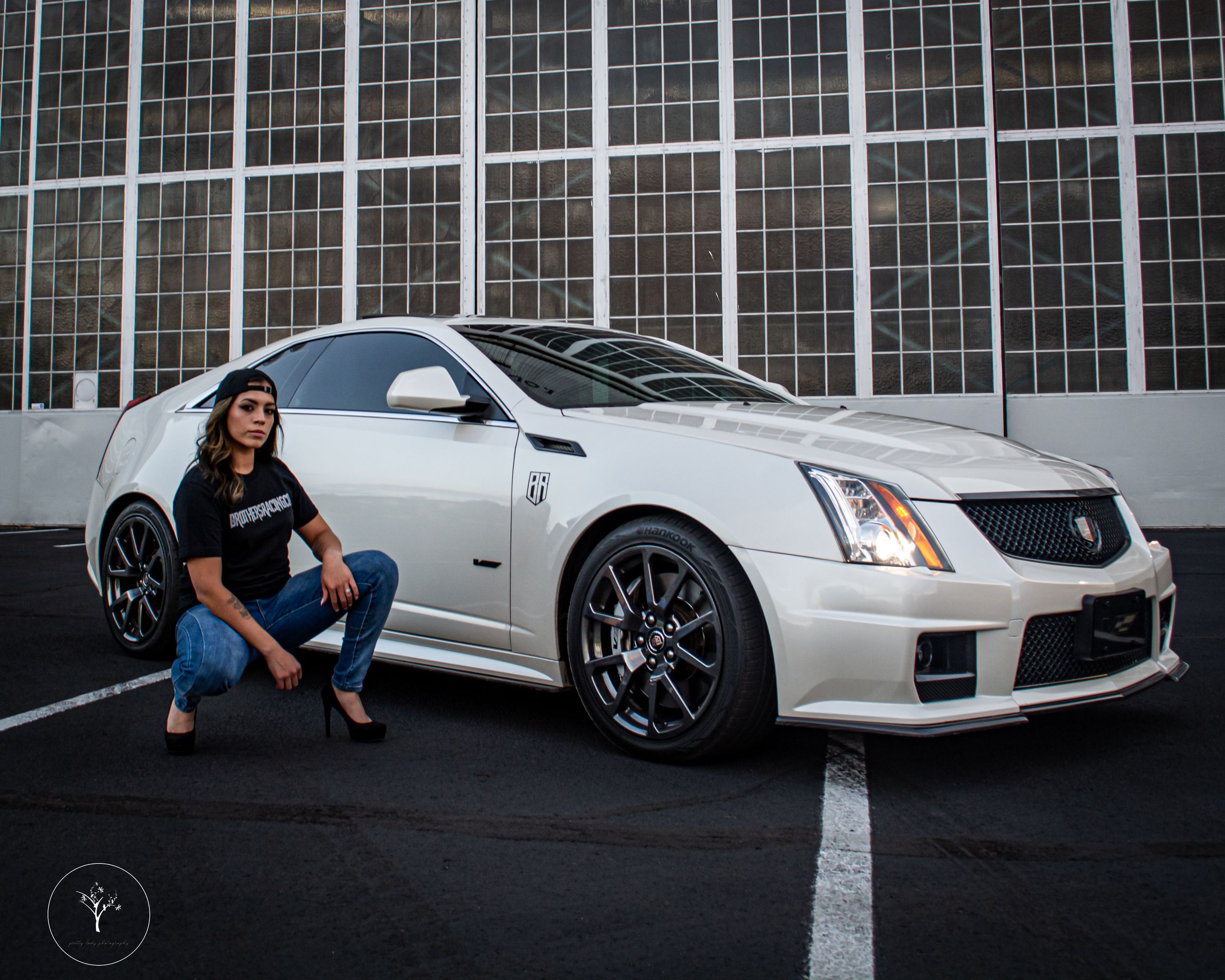 White luxury sports car parked against industrial building with dramatic lighting.