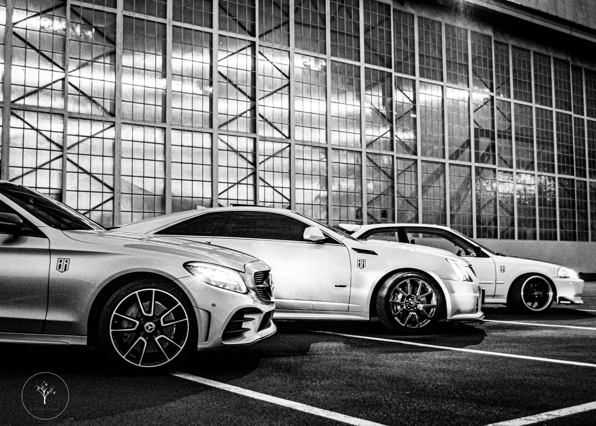 Luxury Mercedes-Benz vehicles parked in a row outside a modern glass building.