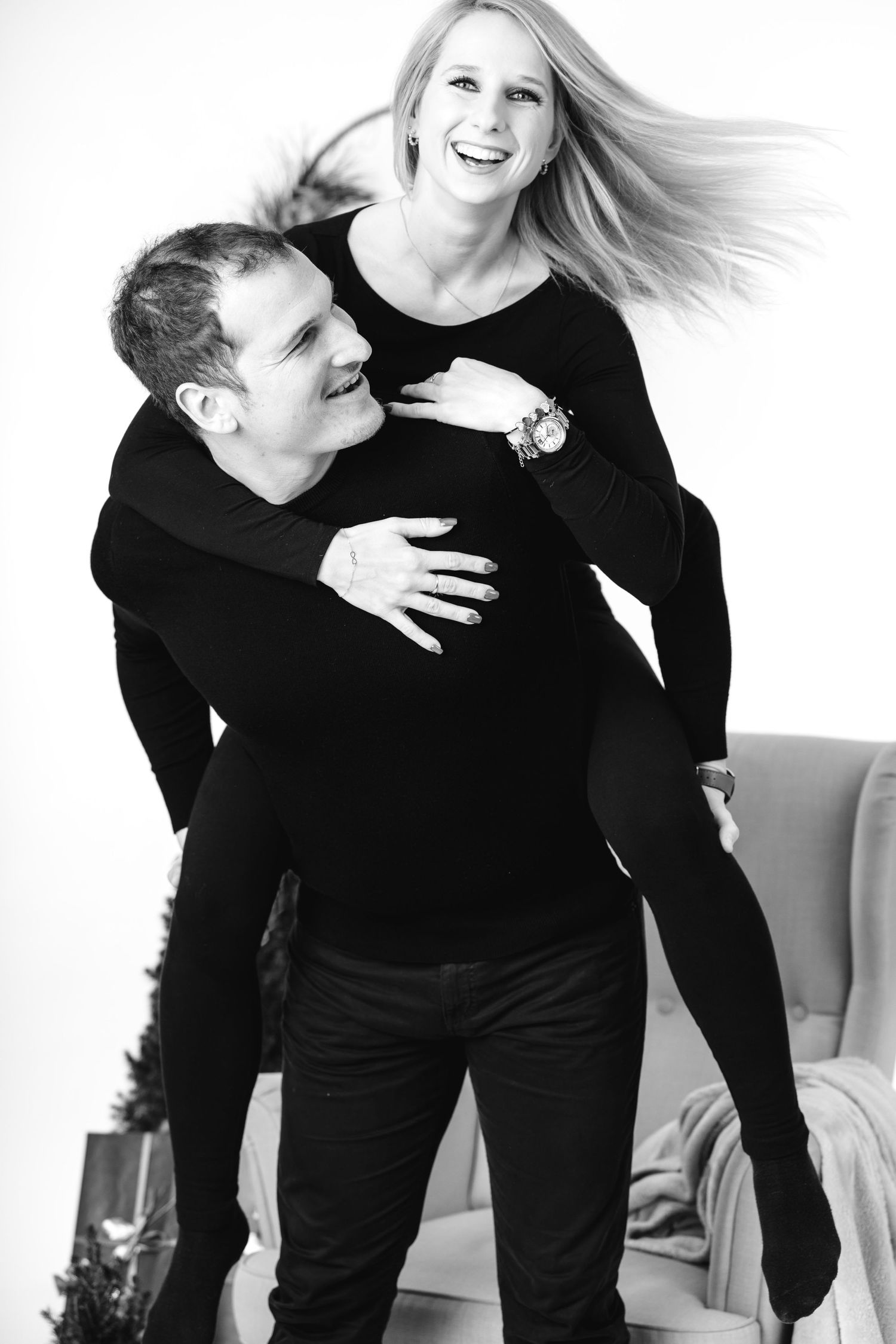 A playful black and white portrait of a couple in matching dark outfits.