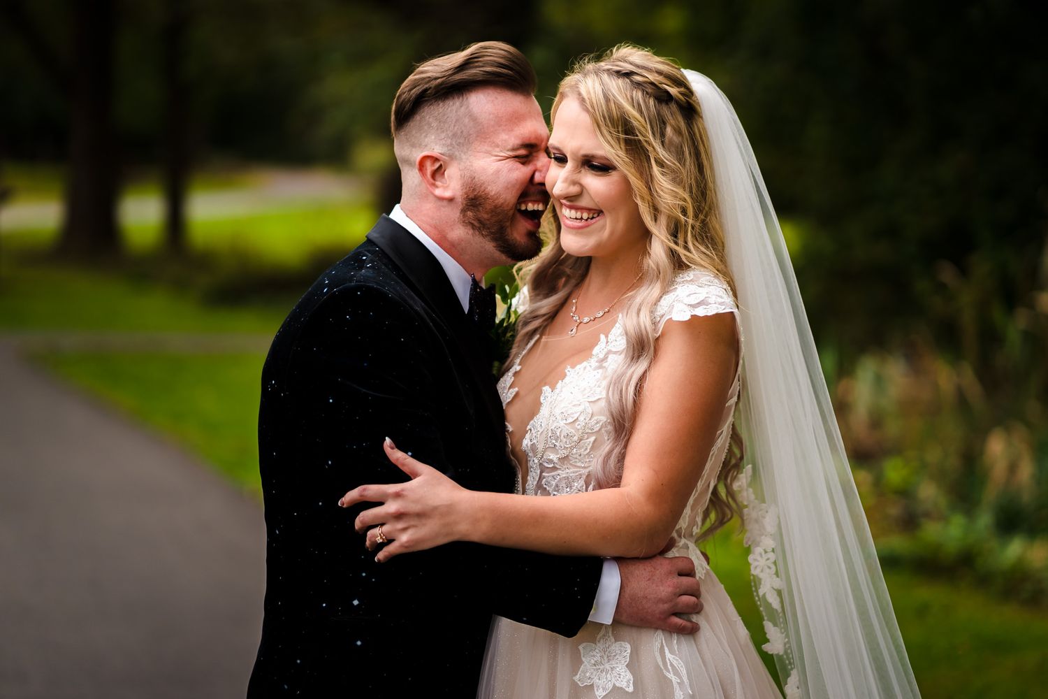 Bride and groom share laughter during outdoor wedding portraits.