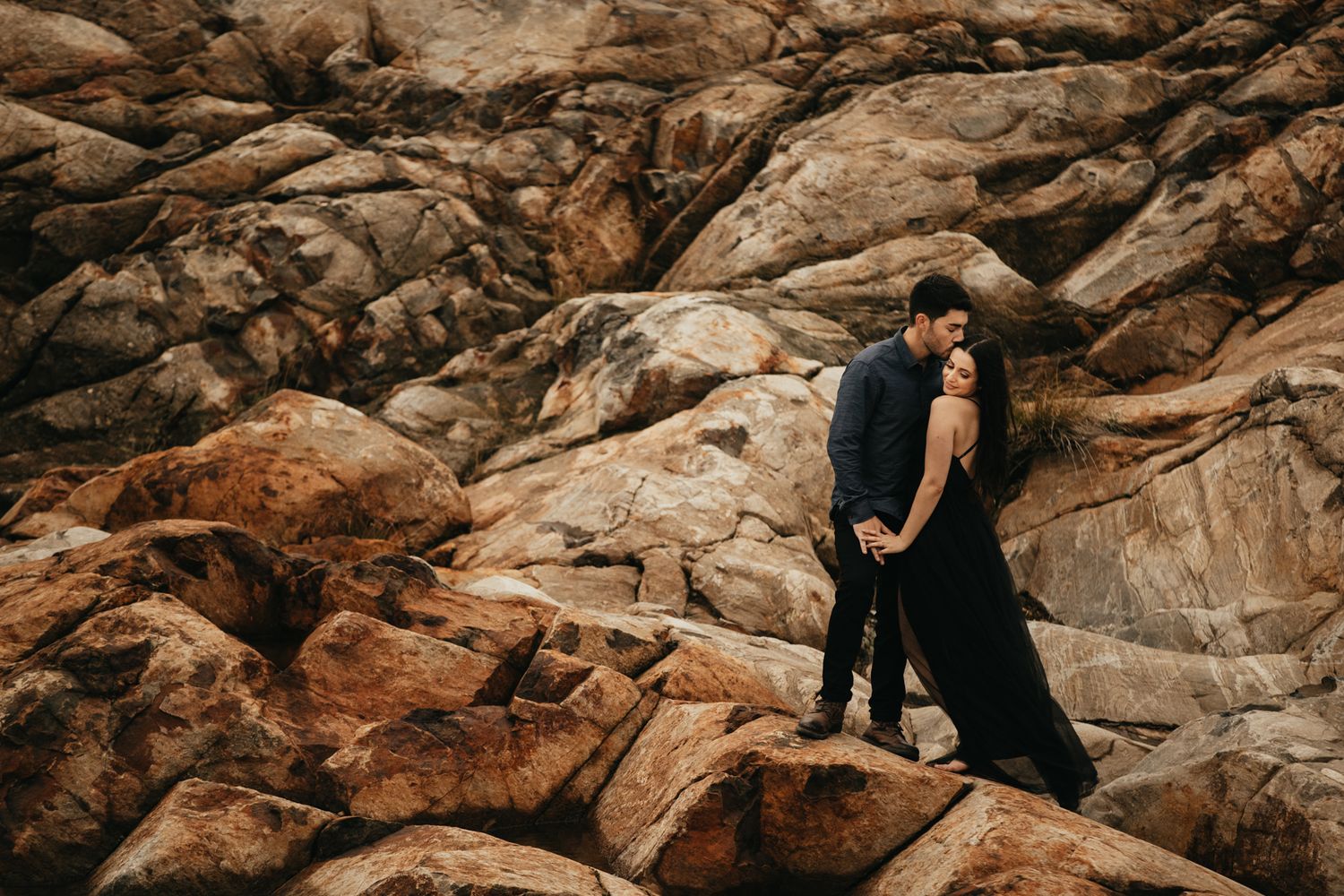 Couple posing on rocky terrain during an outdoor photo session.