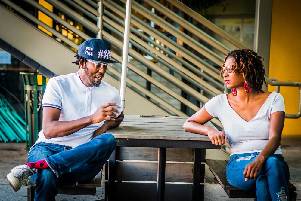 Casual outdoor conversation at urban setting with metal railings in background.