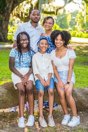 Family of five poses together on rock outdoors wearing coordinated summer outfits.