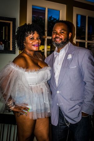 Couple dressed elegantly pose together at an indoor event.
