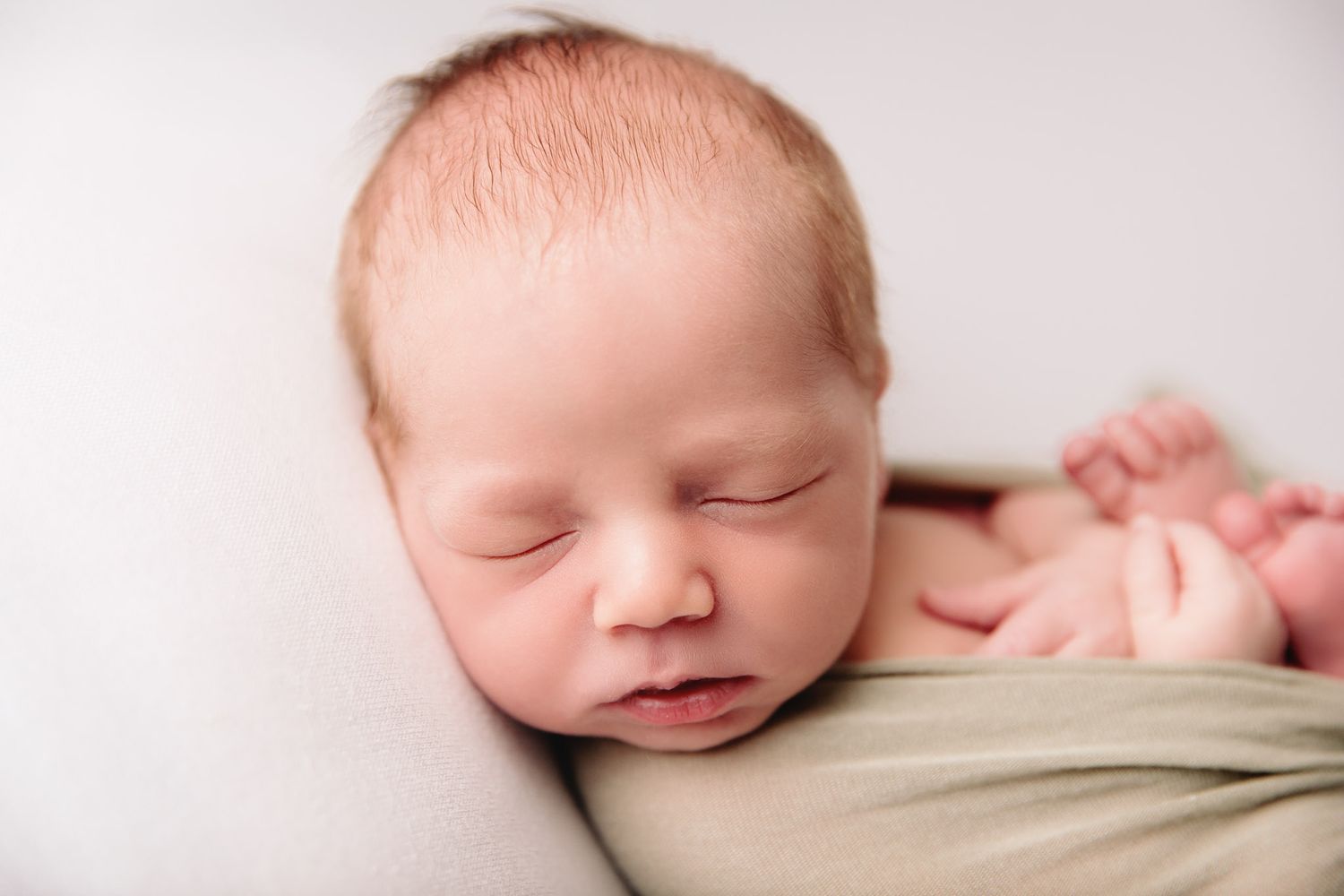 close up of newborn on white blanket backdrop
