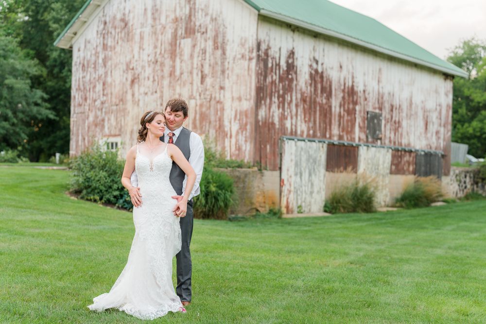Wedding couple poses in front of a weathered rustic barn on their special day.